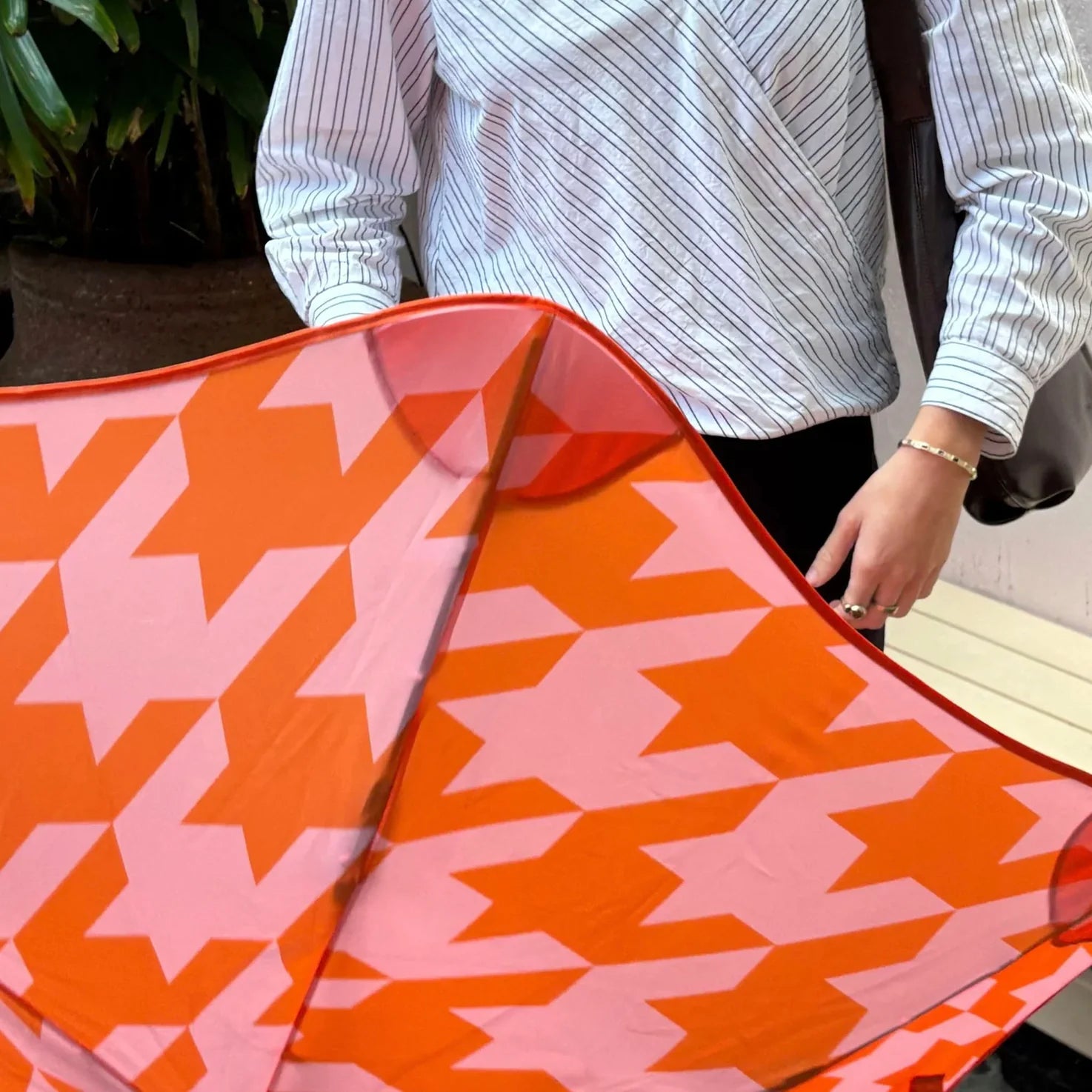 Person holding Orange and pink patterned Blunt umbrella