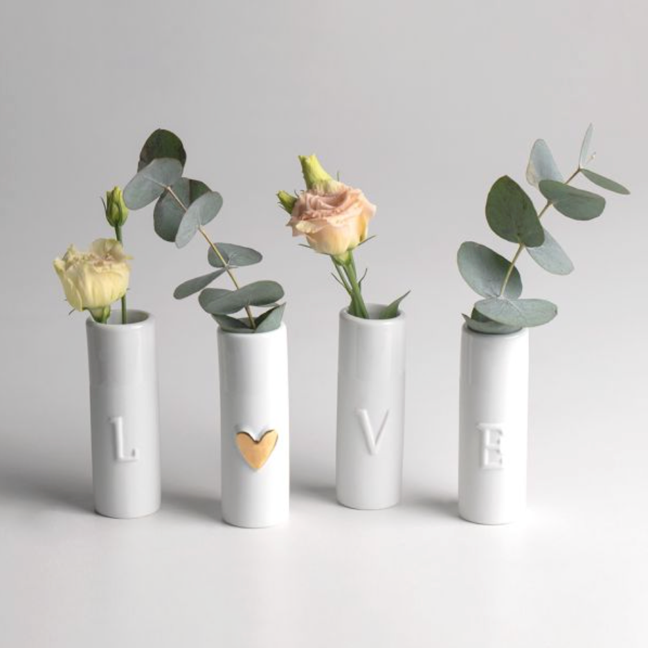 Four white cylindrical vases with decorative elements on a light gray background