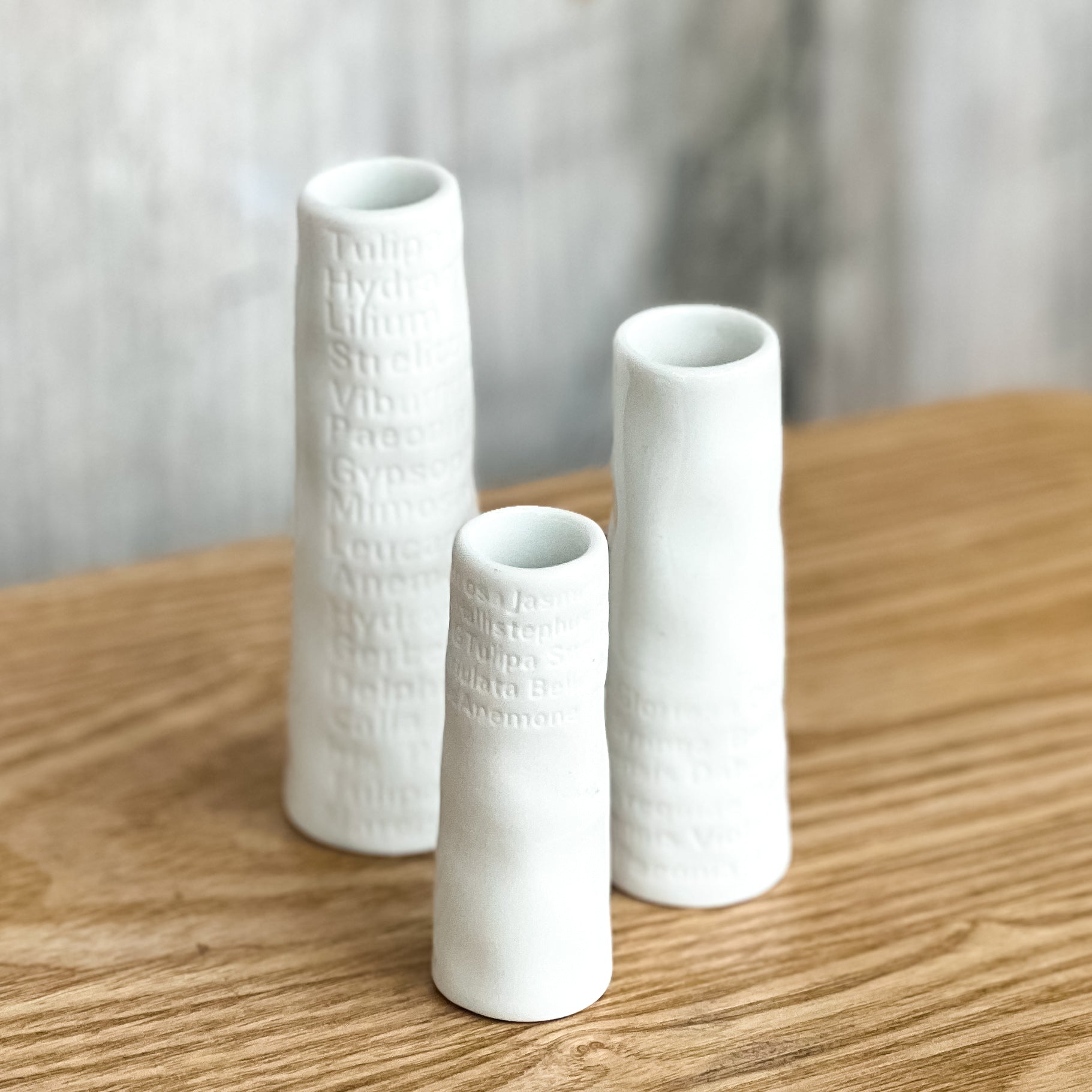 Three white textured vases on a wooden surface with a blurred background