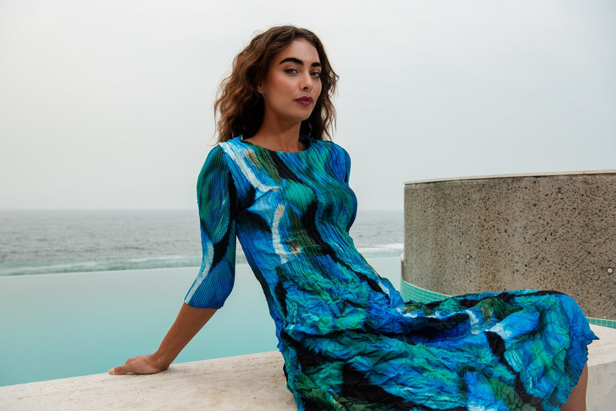 A woman sitting on the edge of a pool wearing a blue patterned dress