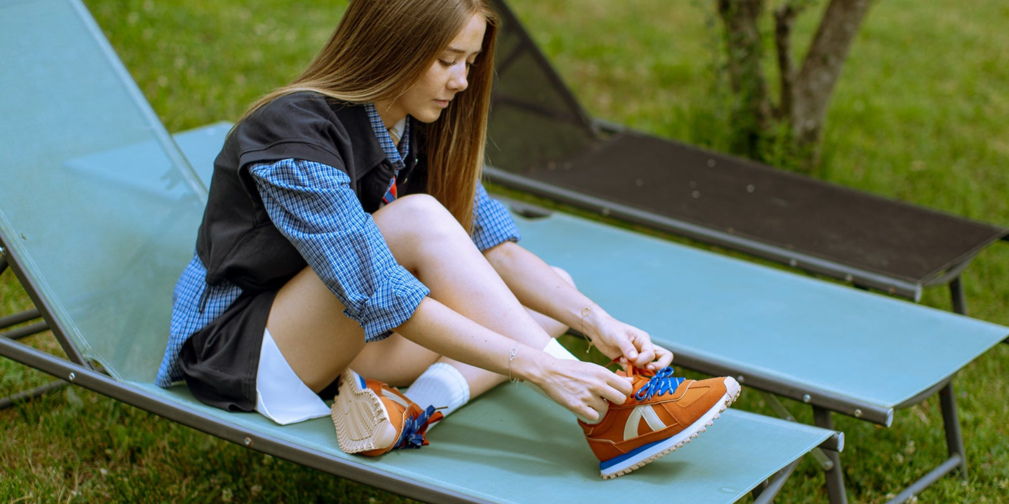 A pair of mustard yellow and blue sneakers on legs in the air