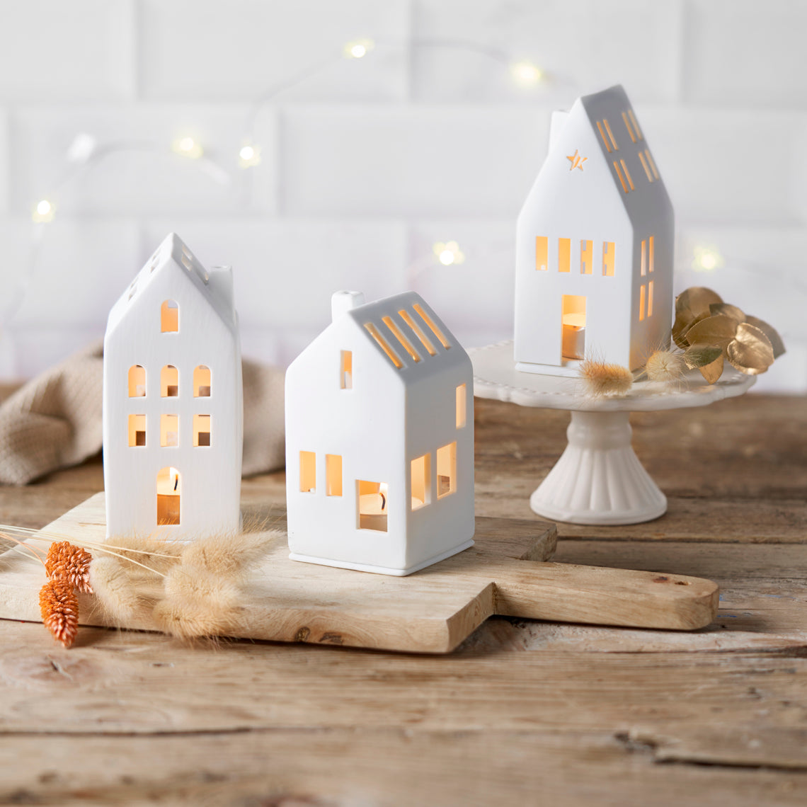 White porcelain house shaped tea light holders on a wooden table
