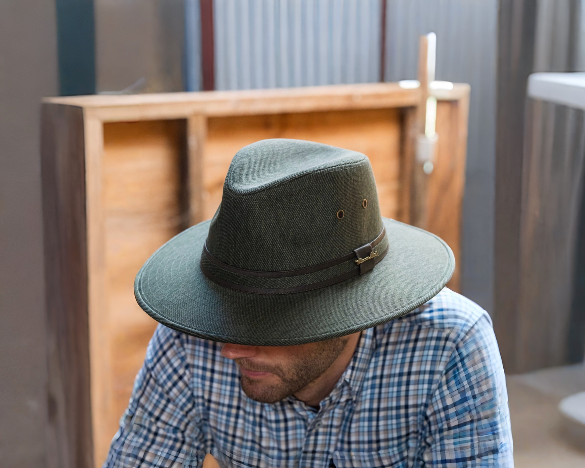 A man wearing a green hat and a blue checkered shirt