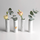 Four white cylindrical vases with decorative elements on a light gray background